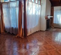 Hermoso living comedor iluminado con amplios ventanales, chimenea ubicada en sector de living, en su interior construida en madera con vigas a la vista, conserva lampara original 