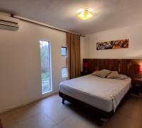 Dormitorio con cama de dos plazas, respaldo rústico de madera, dos veladores con lámparas