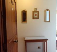 ACCESO PRINCIPAL CON MESA DE ARRIMO CON CUBIERTA DE MARMOL, PEQUEÑOS ESPEJOS EN MURO CON CUADRO DECORATIVOS