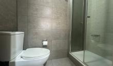 Baño principal con diseño funcional: Lavamanos independiente del área de sanitarios. Zona húmeda equipada con shower door de cristal templado, grifería moderna y revestimientos en porcelanato de alta calidad.