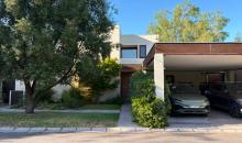 Fachada de casa de dos pisos con antejardín, acceso peatonal y estacionamientos exteriores.