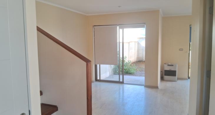 Vista desde la entrada al living. Se aprecia la escala al segundo piso. Debajo de la escala hay una bodega, y a un costado, el baño de visitas.