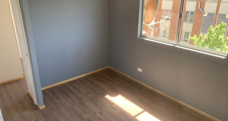 Luminoso dormitorio ubicado en el segundo piso, con piso flotante en tono nogal, muro en color gris que aporta calidez y ventana de buen tamaño que entrega excelente entrada de luz natural.