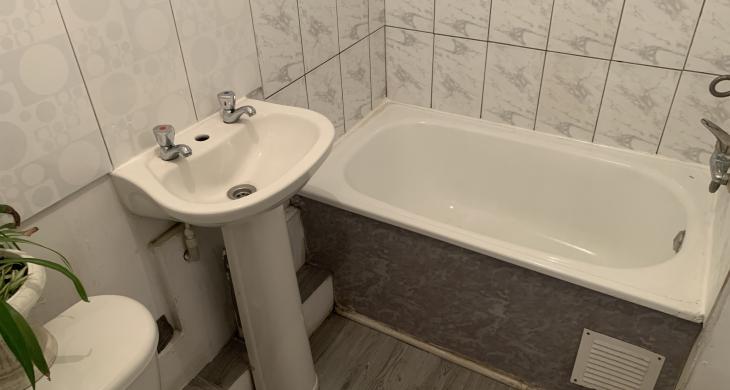  “Baño completo, equipado con tina y lavamanos pedestal, con cerámicos en muros y un espacio funcional de uso diario.”