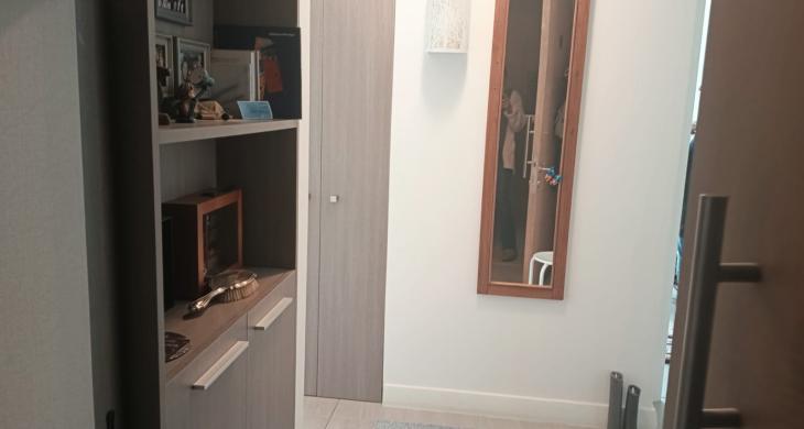 Entrada del departamento que muestra el acceso principal y un espacio de recepción ordenado con mueble incorporado”