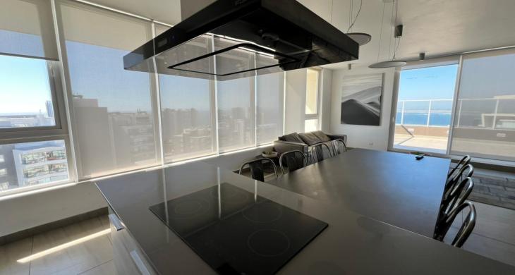 Living iluminado con el mesón de la cocina integrada.