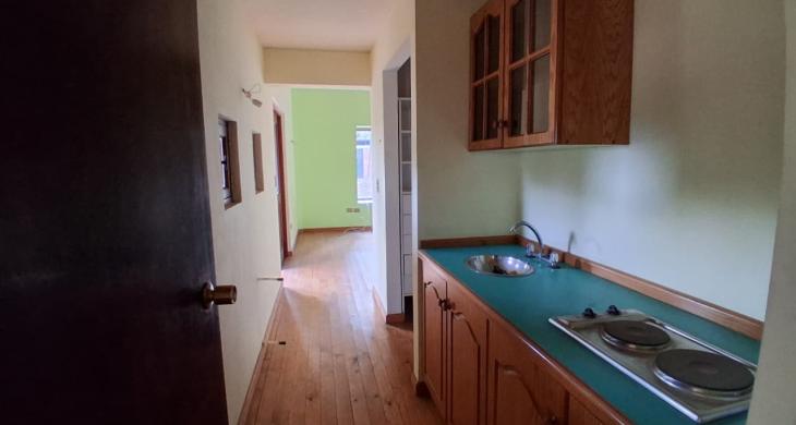 Dormitorio principal. Desde la entrada se observa una estantería, lavaplatos y cocina encimera, otorgando independencia a la suite. 